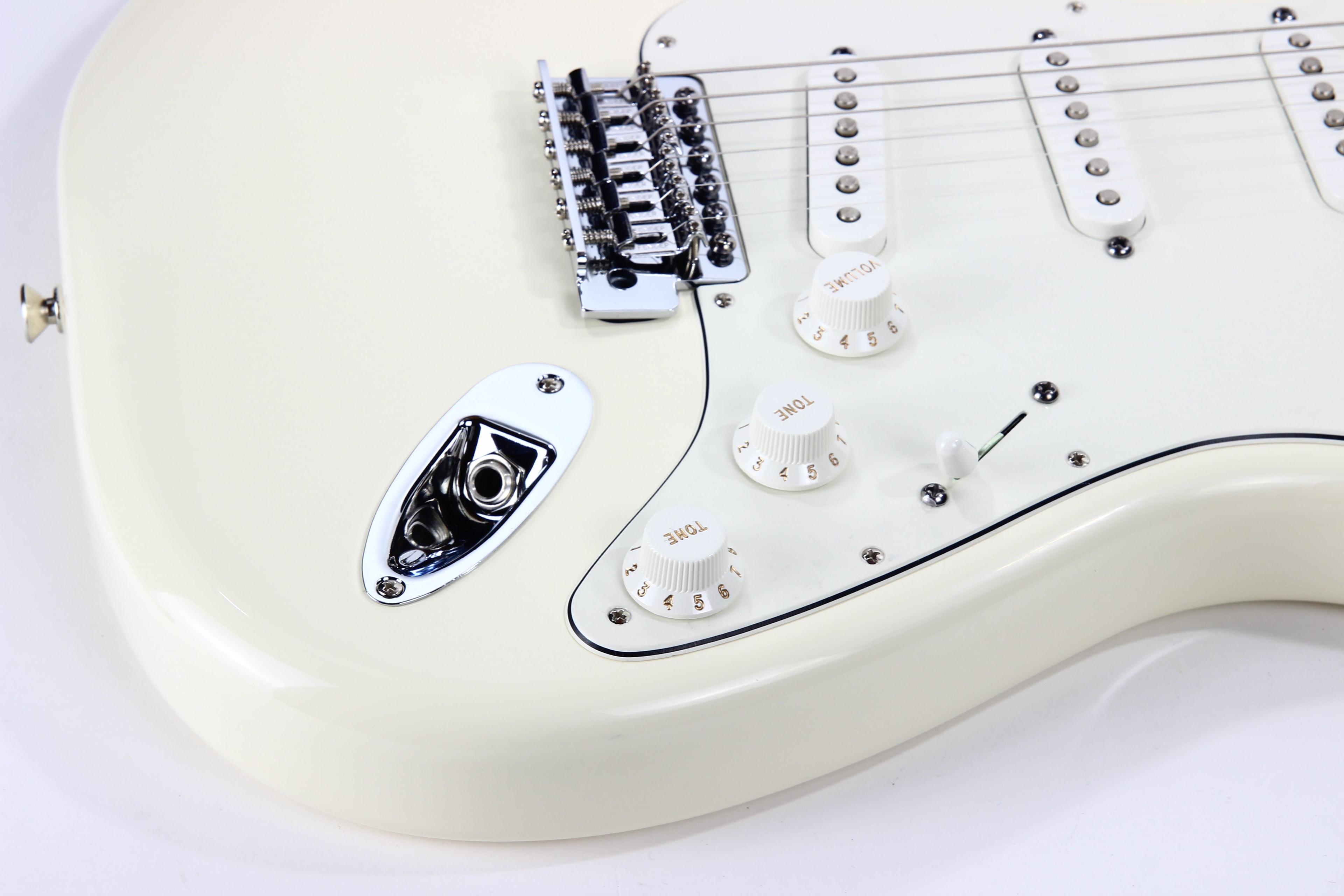 The ribbed white volume knob and gold numbers on a Fender Stratocaster
